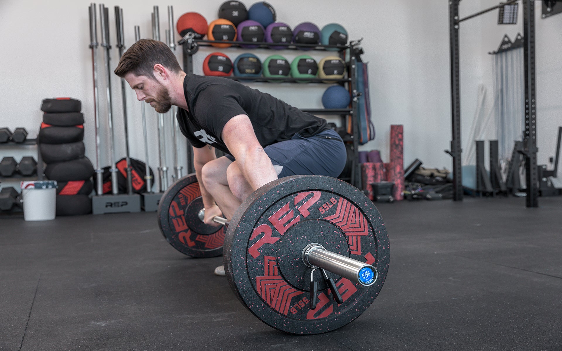 Side view of a male lifter setting up to perform a snatch with a loaded REP Teton Training Bar - 20kg.