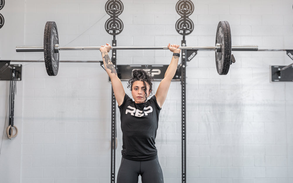 Athlete in the finish position of a clean and jerk using the REP 15kg Teton Training Bar.