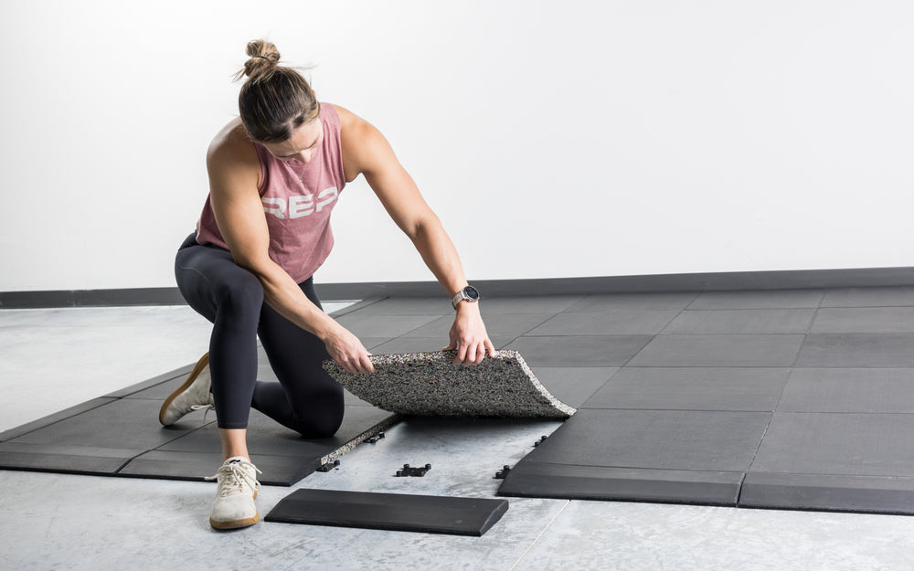 One person installing the REP Fitness Interlocking Tiles with the four-way dowel system and border pieces