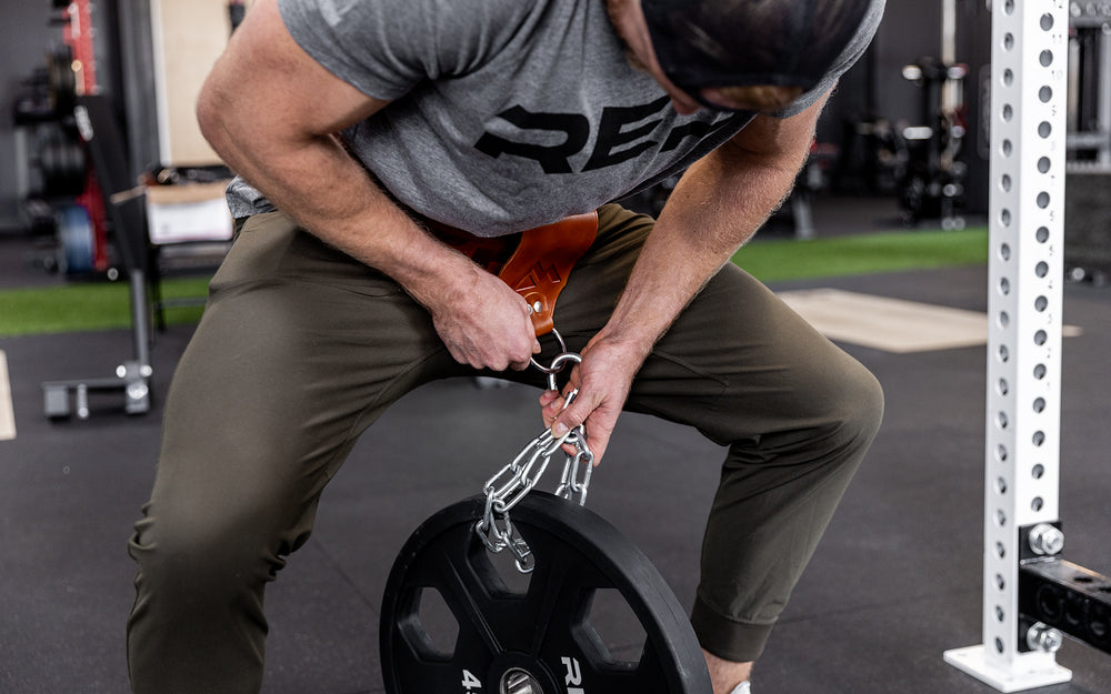 Athlete using the chain and carabiner to attach a 45lb plate to his REP Leather Utility Loop.