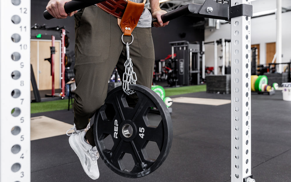 Athlete is performing a weighted dip using the REP Leather Utility Loop.