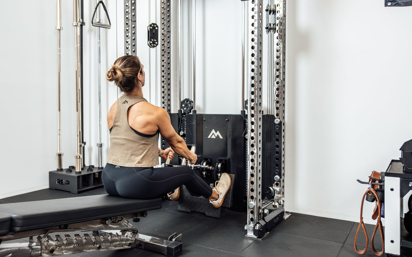 An athlete performing a low cable row on the Wall-Mounted Ares™ 2.0 while seated on a REP BlackWing™ bench