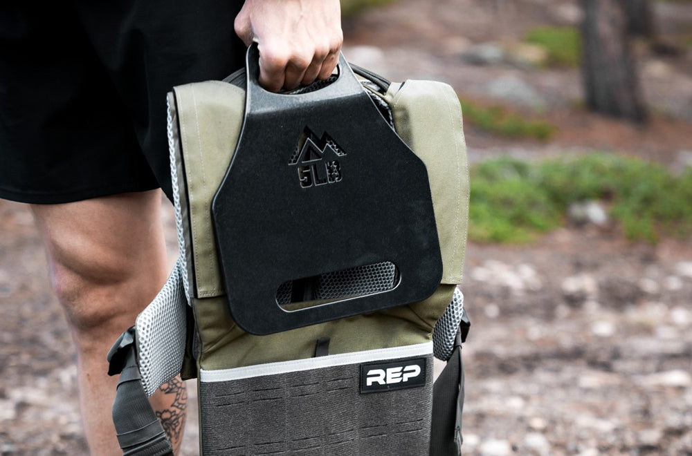 Athlete carrying the olive Strata Weight Vest and 5lb plate
