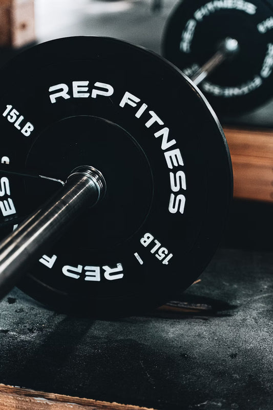 Bars & Weights - 15lb REP Fitness black bumper plates shown on a barbell with spring clips