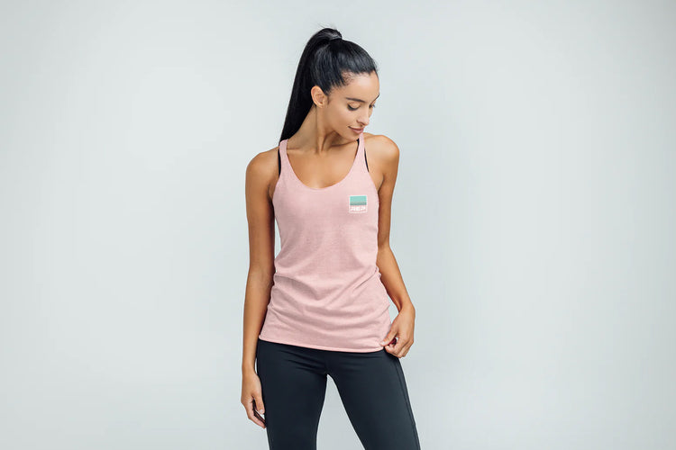 Woman wearing a Rise Tri-Blend Tank in pink with a logo on a gray background