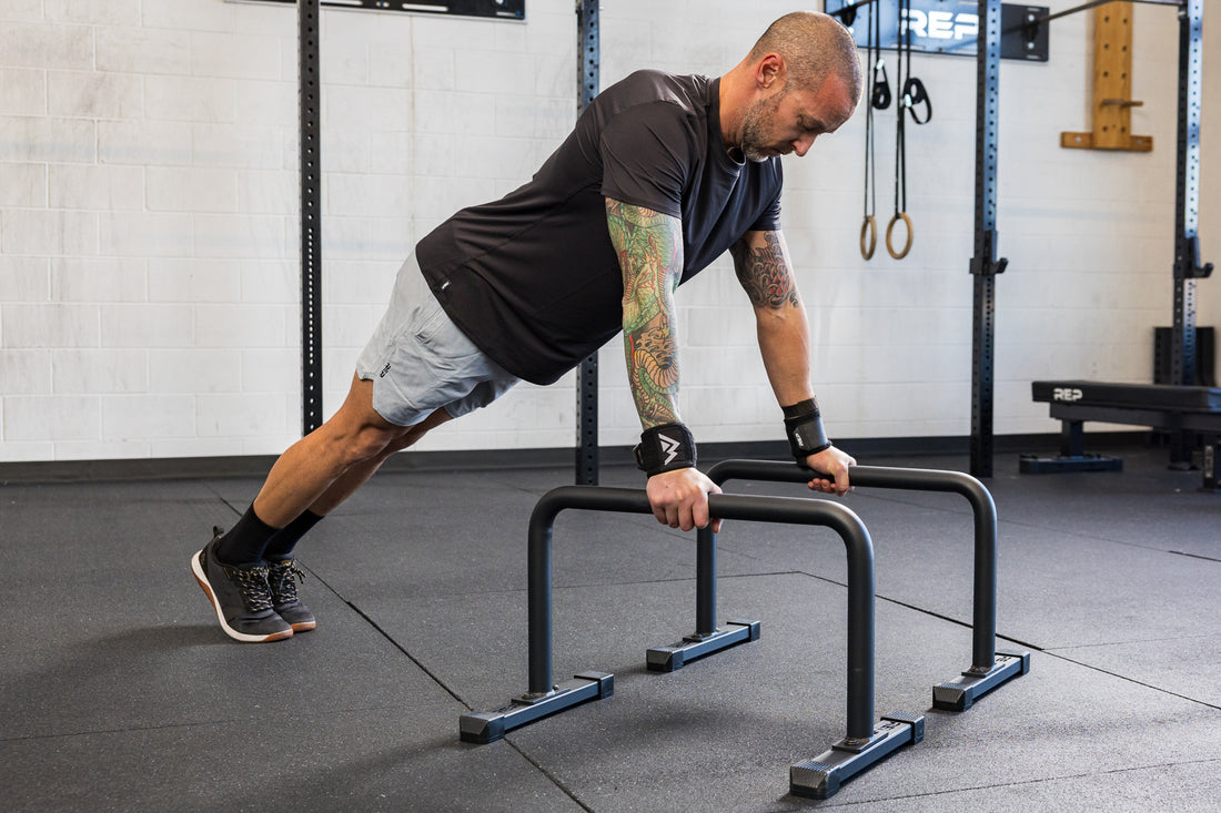 Athlete in an extended push-up position on the REP Fitness Parallette Bars