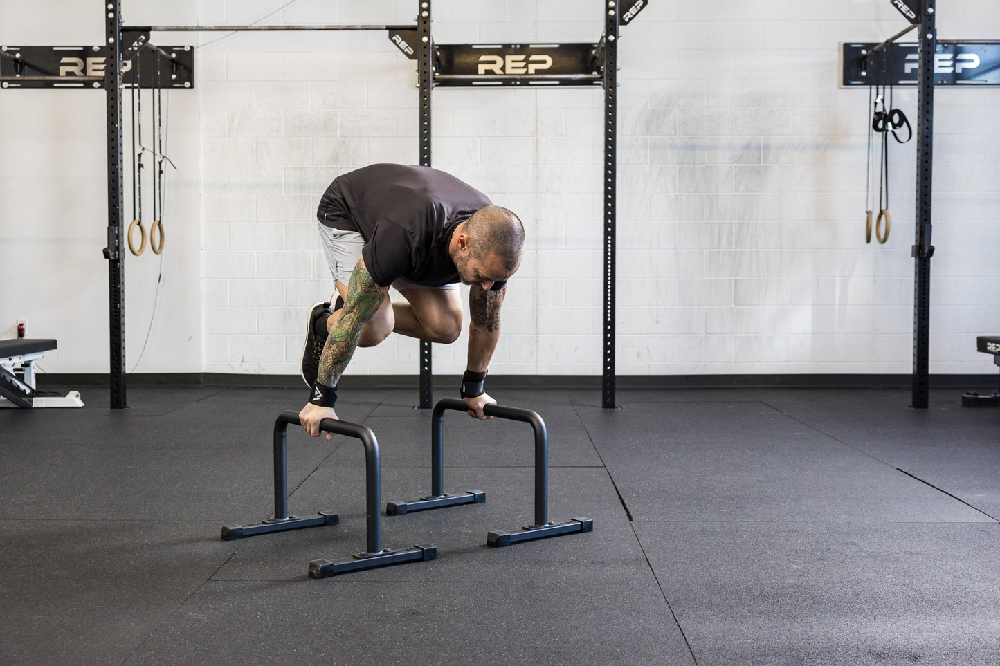 Athlete doing a knee tuck on the REP Fitness Parallette Bars