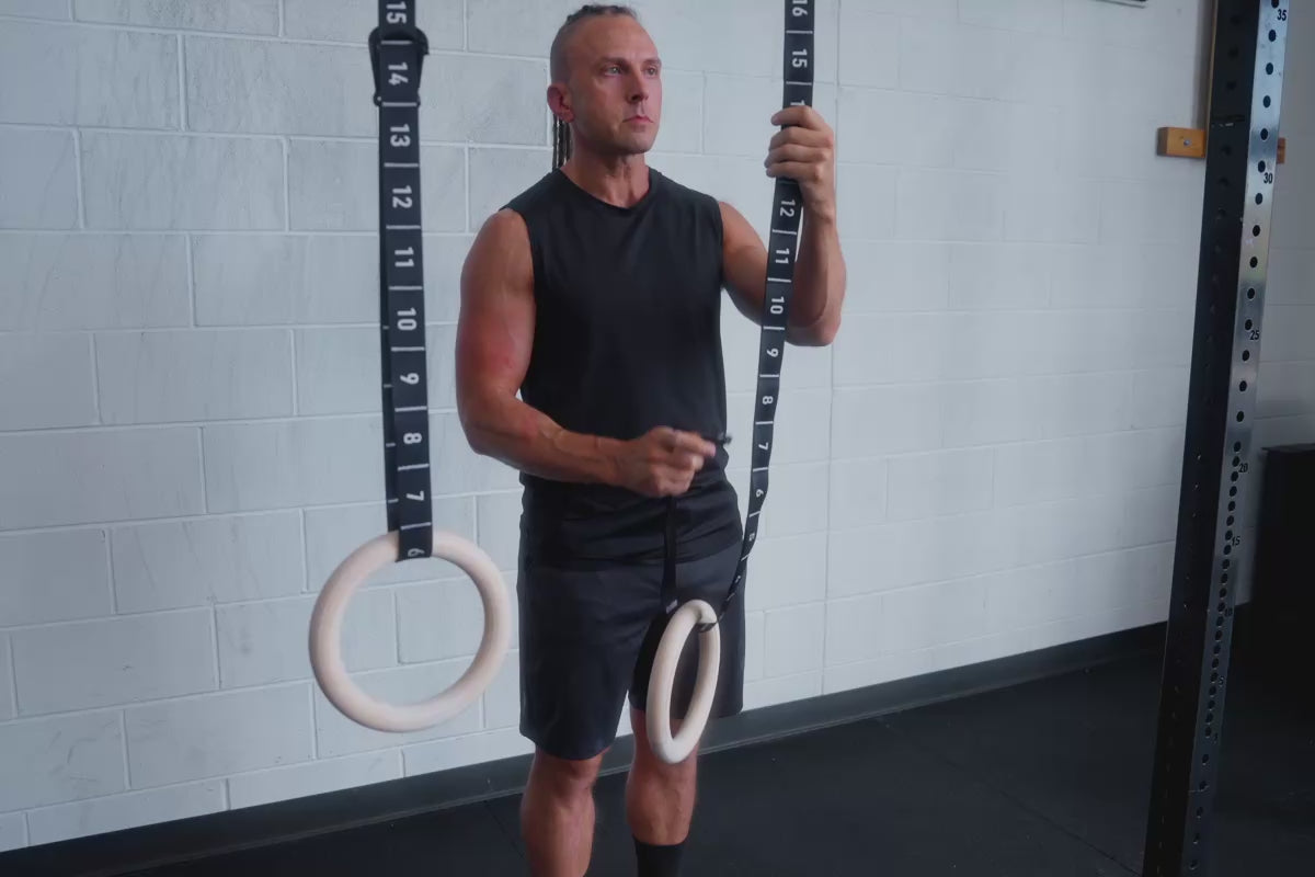 An athlete attaching the carabiner to the numbered adjustment sections of the REP Competition Gymnastic Straps and Wood Rings