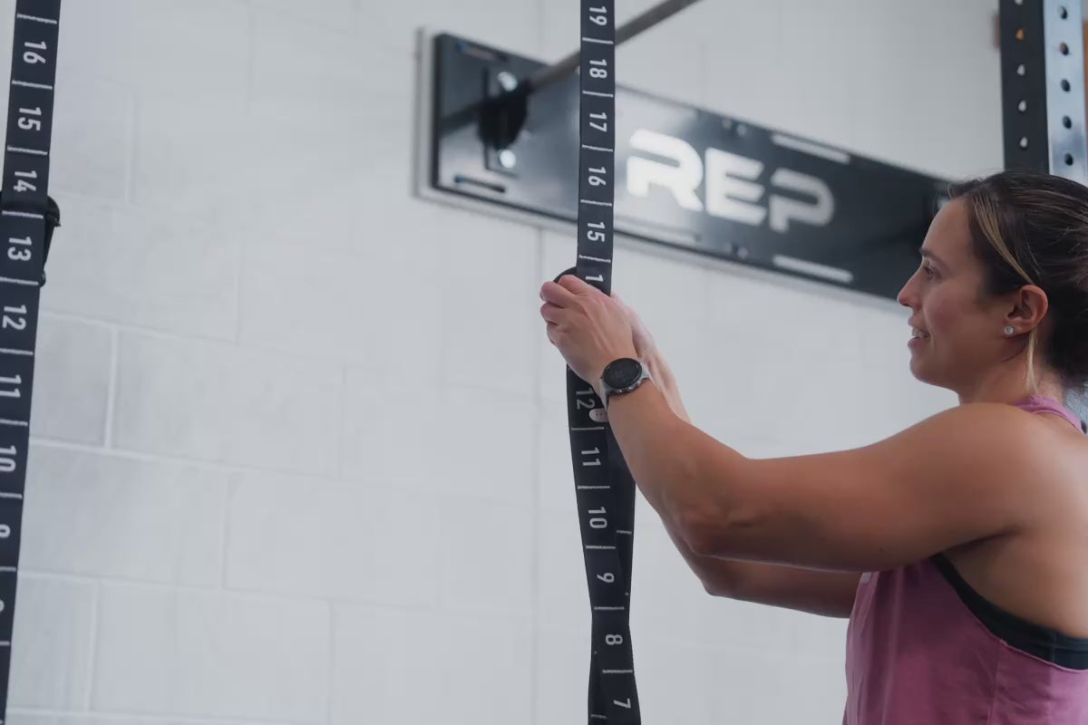 An athlete locking the carabiner to the numbered adjustment sections of the REP Competition Gymnastic Straps and Wood Rings