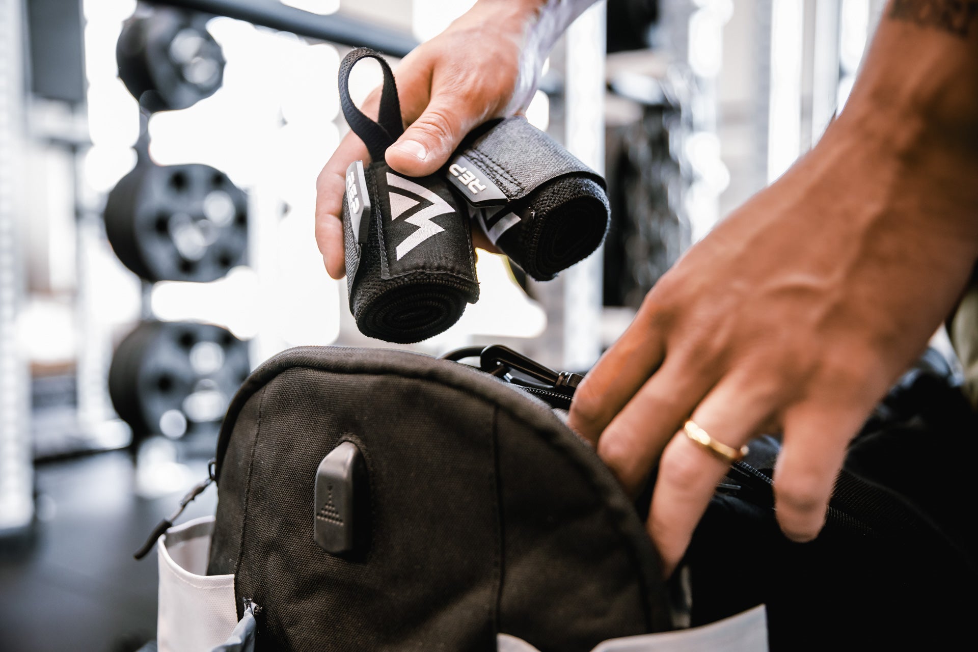 Close up shot of an athlete putting their REP Wrist Wraps into a side pocket of their duffel bag