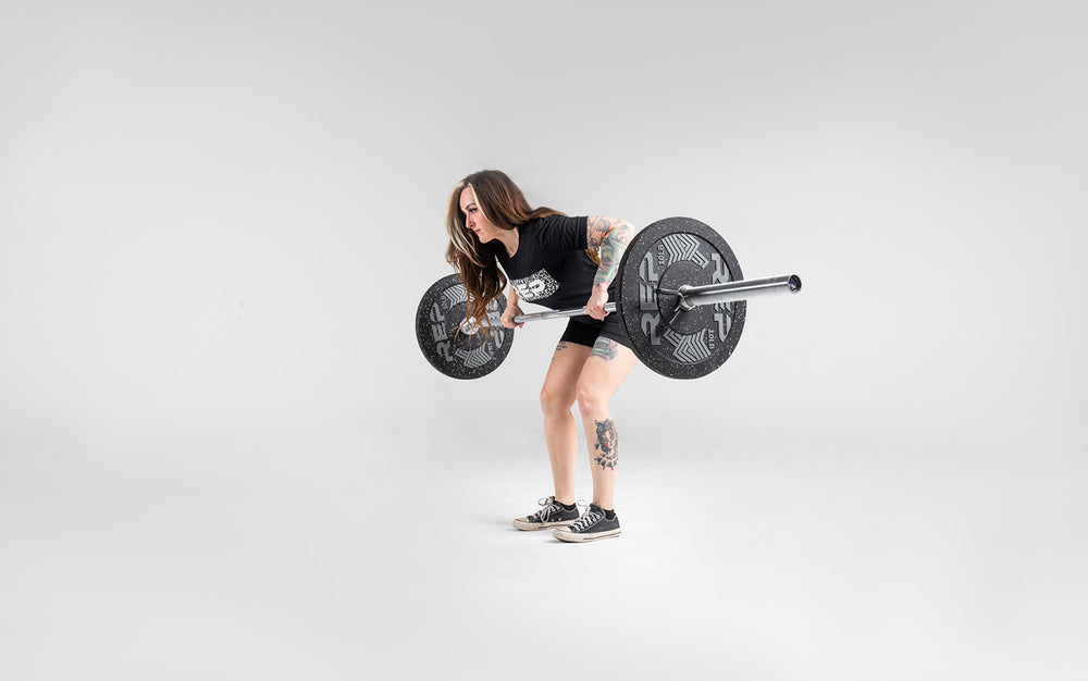 Lifter performing a bent over row with a barbell loaded with a pair of 10lb pinnacle bumper plates.