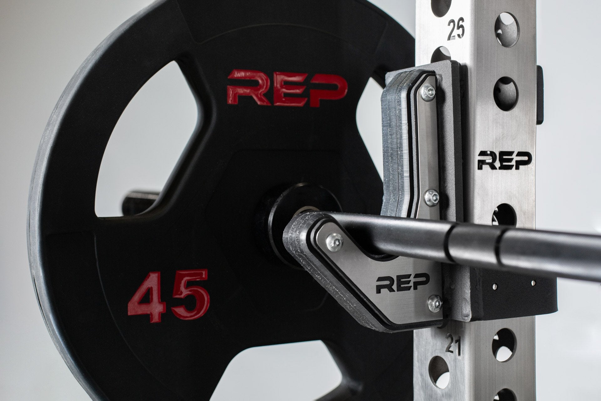 Close up view of a 45lb Rubber Coated Olympic Plate from the inside view of a barbell racked on flat sandwich j-cups on a PR-5000 power rack.