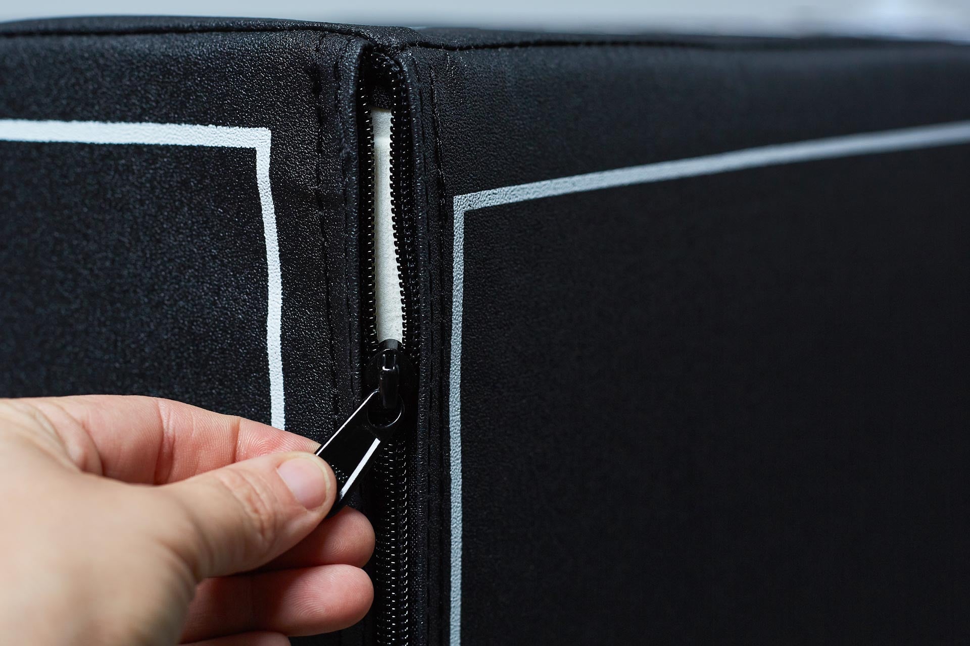 Close-up view of an individual unzipping the soft plyo box to show the soft foam cover.