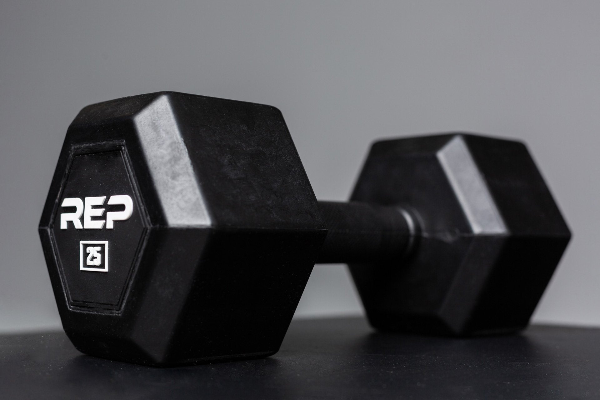 Angled view of a 25lb Rubber Coated Hex Dumbbell showing off the white 