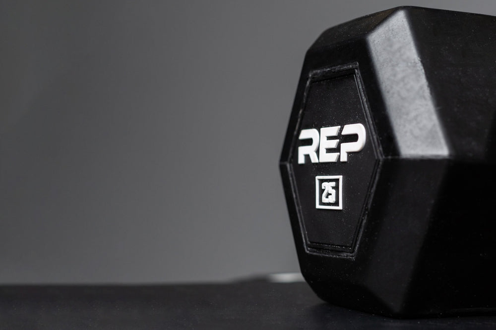 Close-up view of the hexagon head of a 25lb Rubber Coated Hex Dumbbell showing off the white "REP" logo and weight marking.