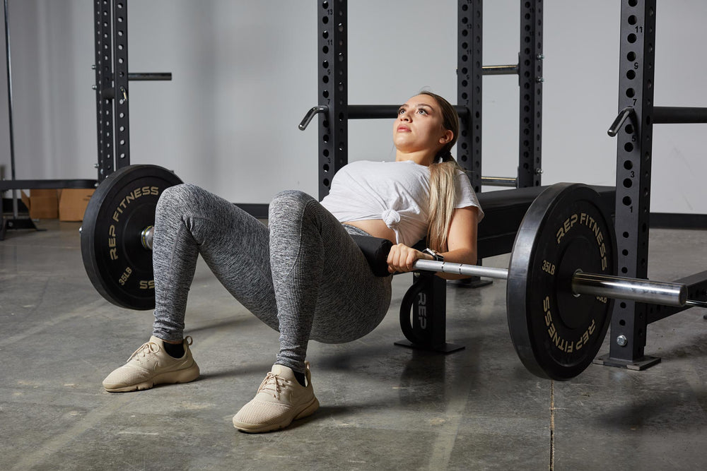 Lifter using the REP barbell shoulder pad for comfort while performing barbell hip thrusts.