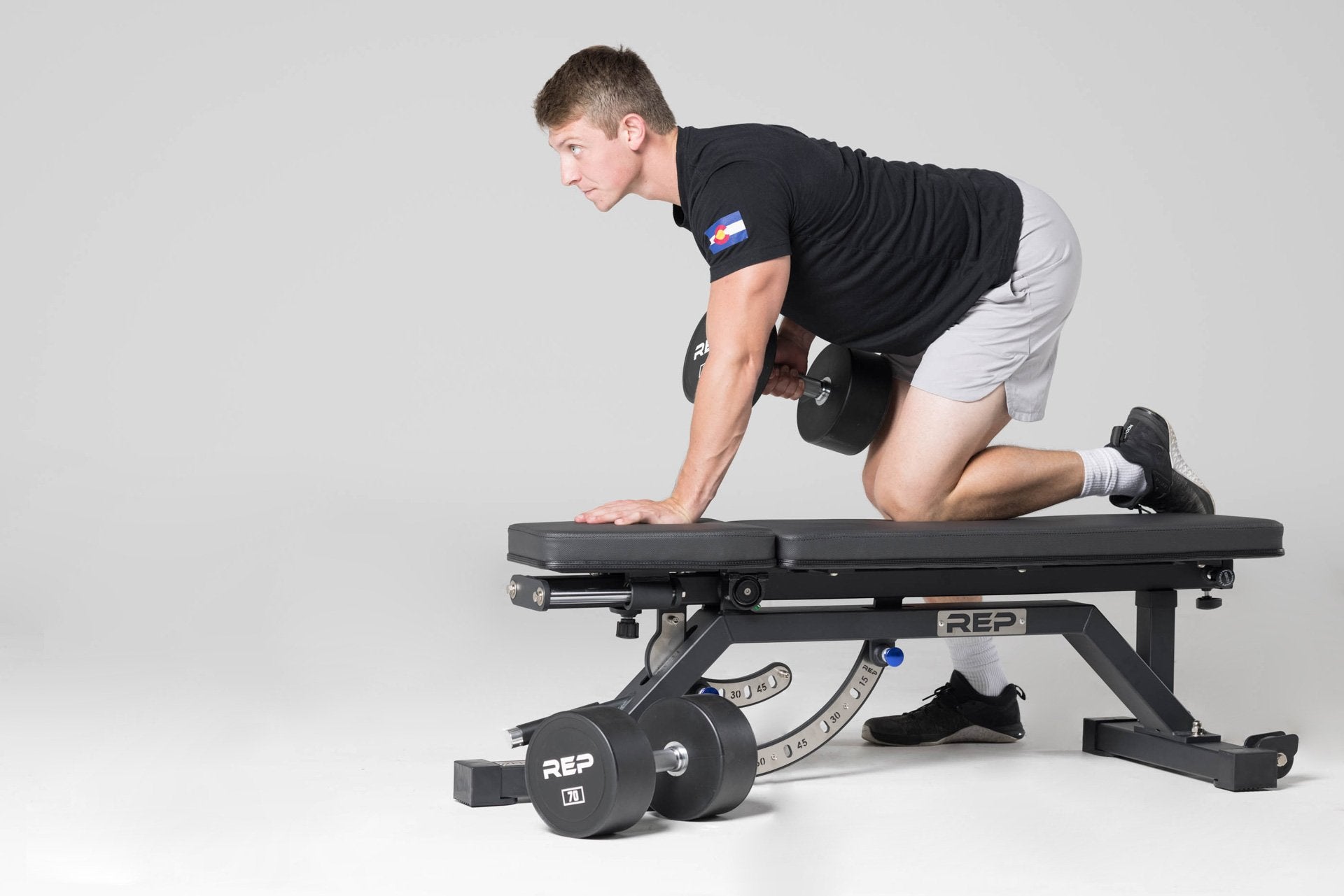 Lifter positioned on an AB-5000 bench performing a single-arm row with a 70lb Urethane Dumbbell.