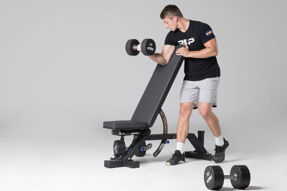 Lifter using an AB-5000 bench in an incline position to perform a preacher curl with a 25lb Urethane Dumbbell.