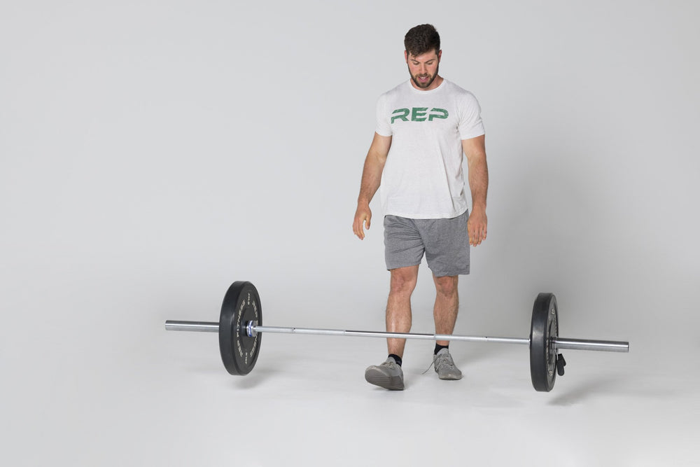 Lifter shown standing above a barbell he just dropped loaded with a pair of 45lb Black Bumper Plates.