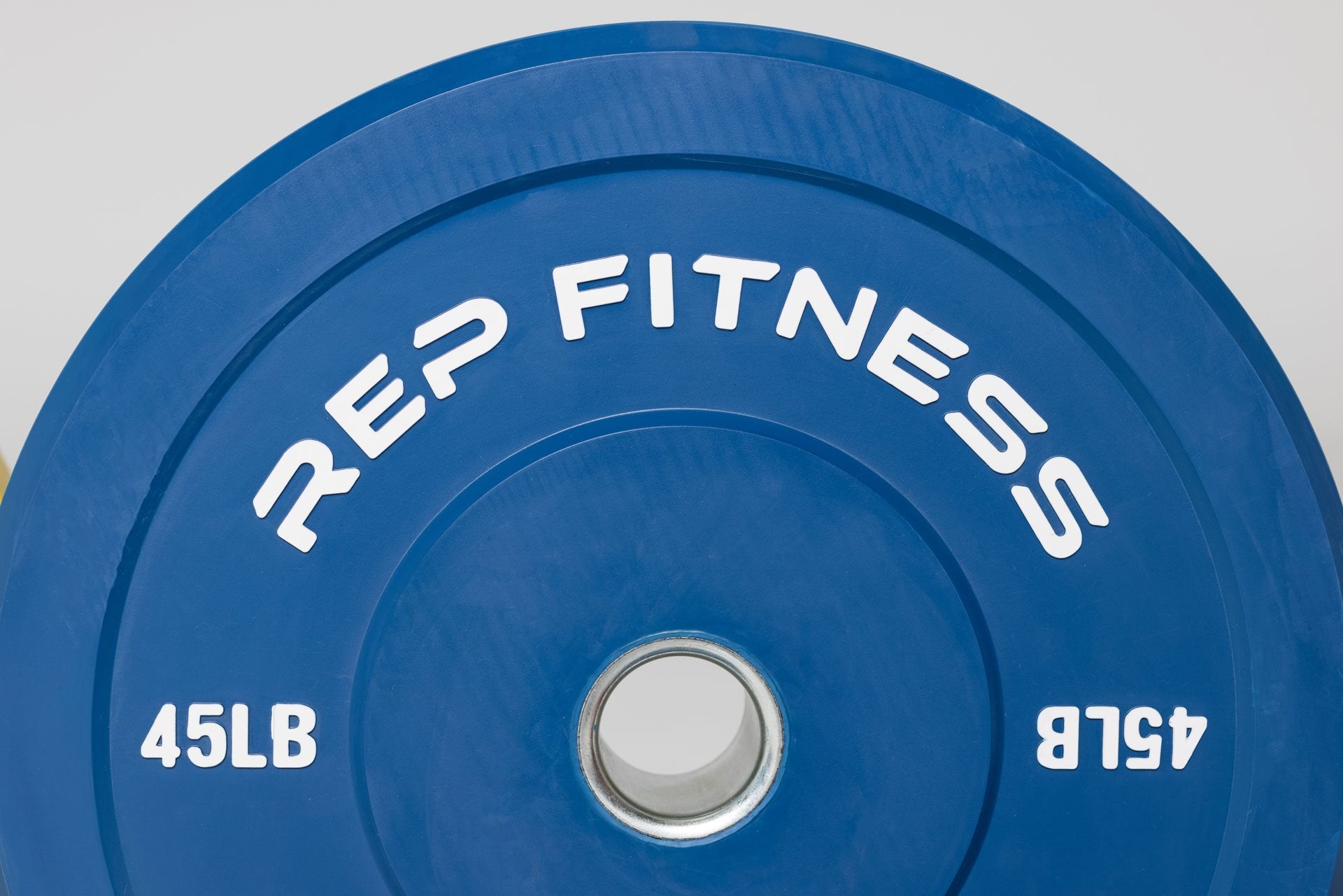 Close-up view of blue 45lb color bumper plate showing white raised 