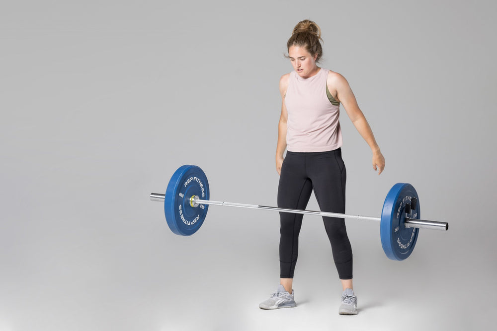 A barbell loaded with a pair of blue 45lb colored bumper plates falling to the ground after being dropped by a lifter.