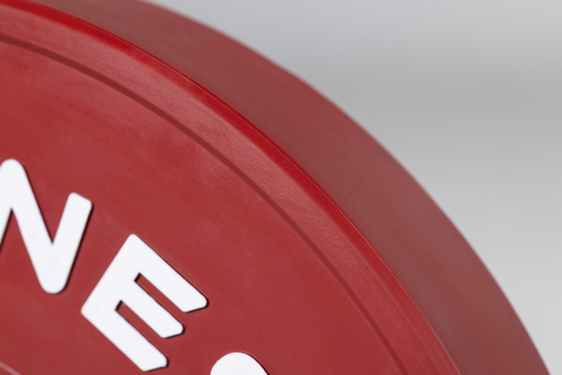 Close-up view of the edge of a red 55lb competition bumper plate.