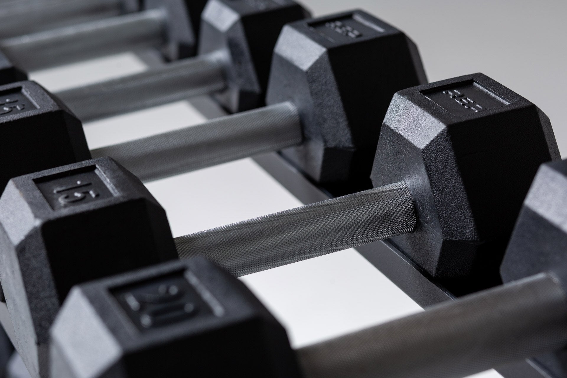 Close-up view of the 15lb pair of a 5-50lb Hex Dumbbell Set being stored on the top shelf of a REP Dumbbell Rack.