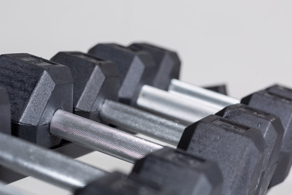 Side view of the 10, 15, and 20lb pairs of a 5-50lb Hex Dumbbell Set being stored on the top shelf of a REP Dumbbell Rack.