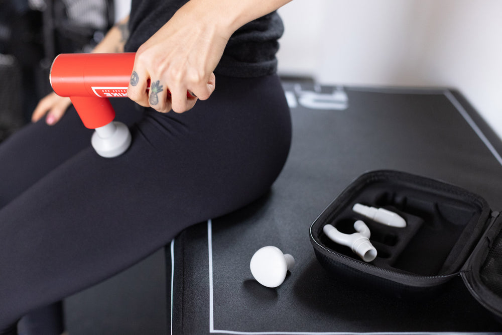 Individual using the Rapidstrike Massage Gun on her upper thigh.