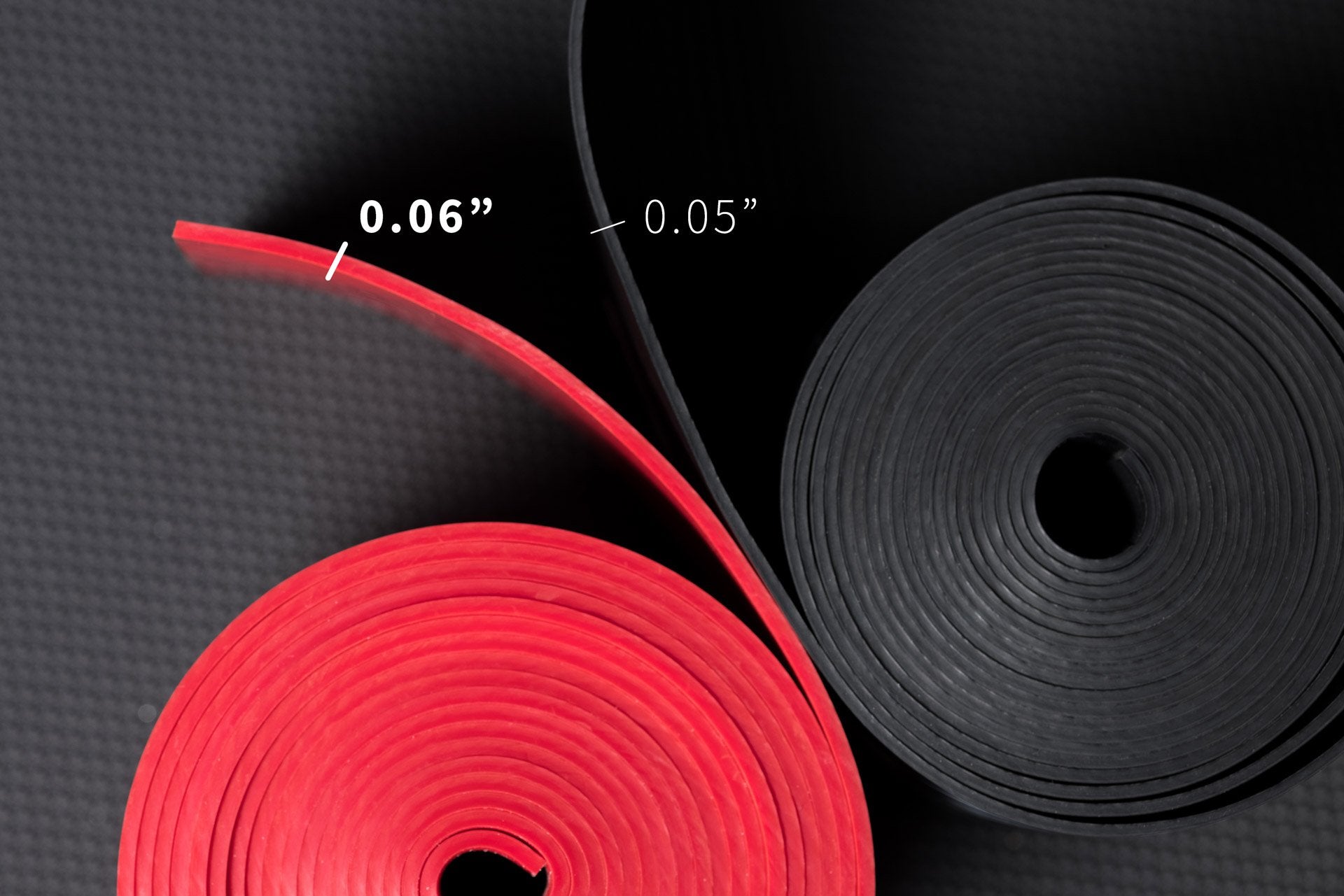 Overhead view a pair of rolled up floss bands showing that the black has a 0.05