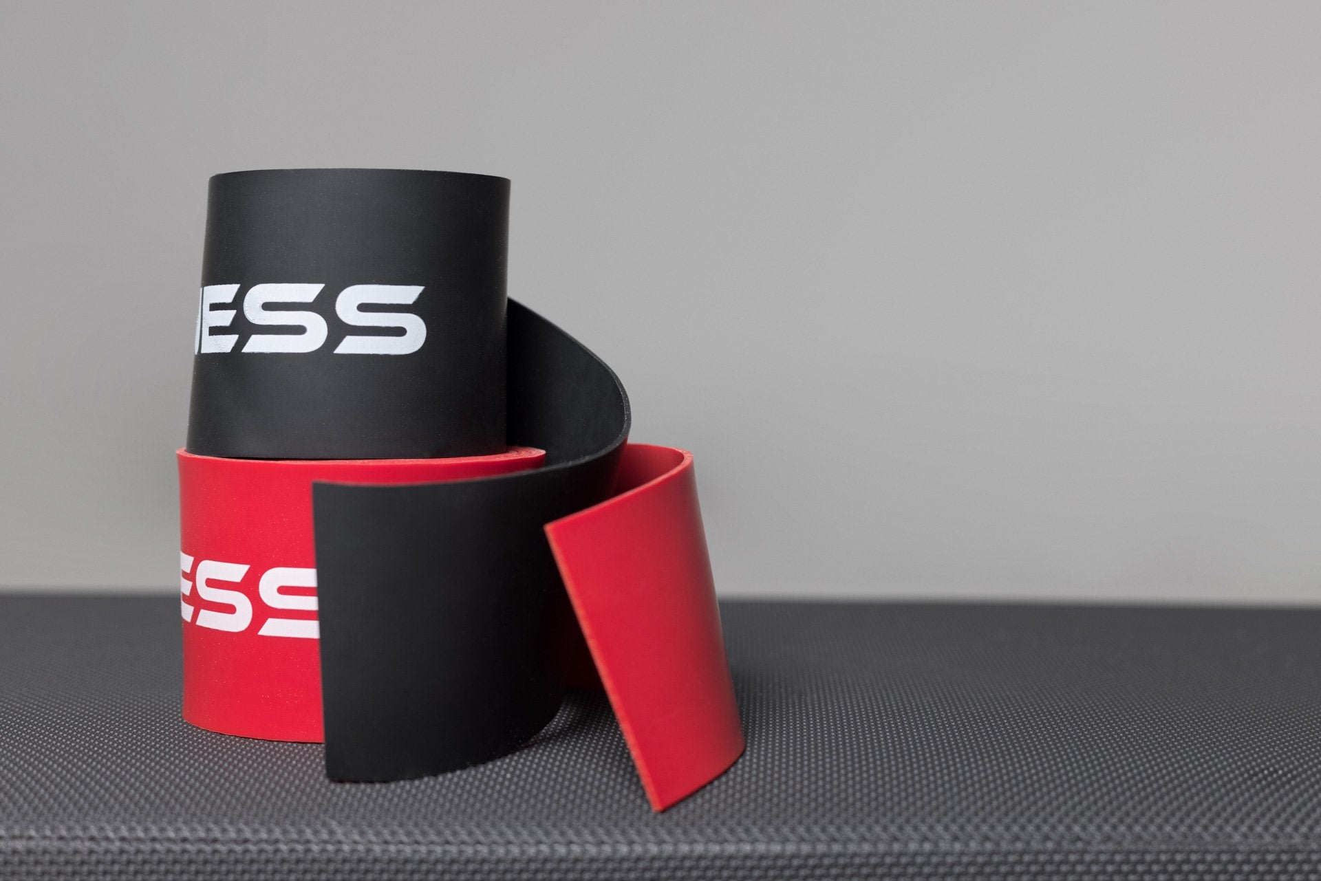 A pair of stacked REP Floss Bands; black on top and red on bottom.