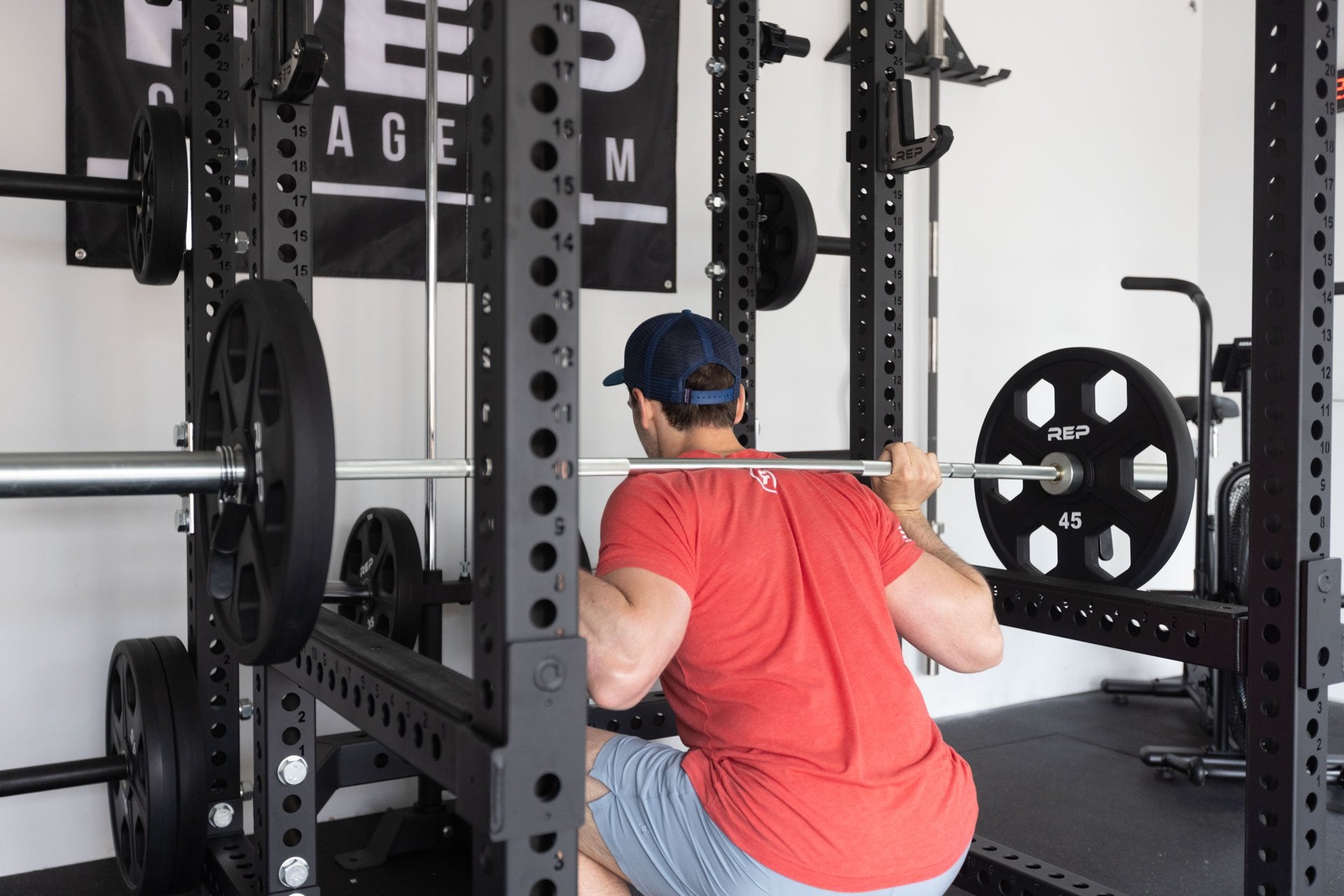 Lifter in the bottom of a squat with a barbell loaded with a pair of 45lb Urethane Coated Equalizer Plates in the back rack position inside of a 6-post PR-5000 power rack.