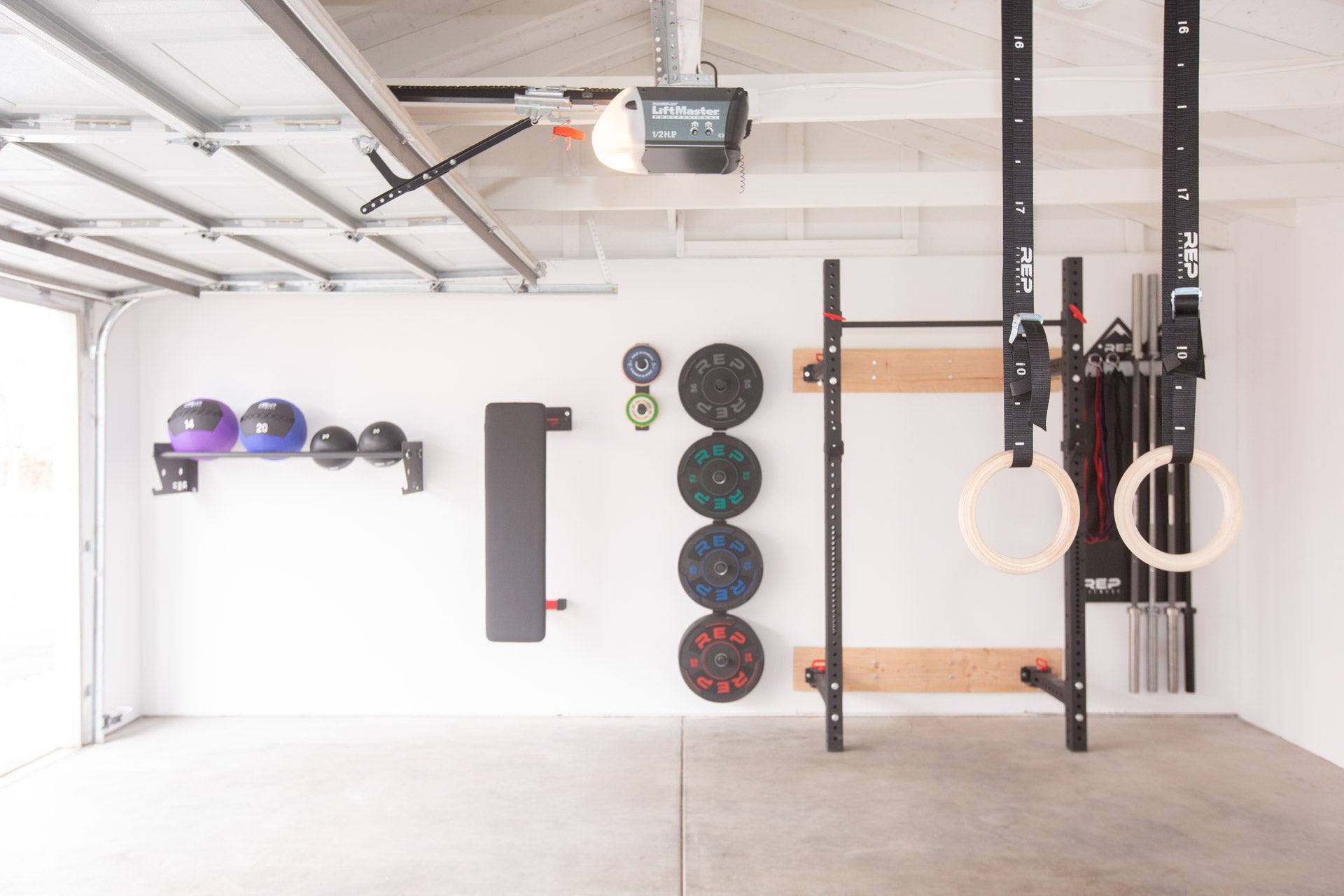 A garage gym showcasing a variety of REP space-saving wall storage loaded with equipment including the single and double Wall Mounted Plate Storage.