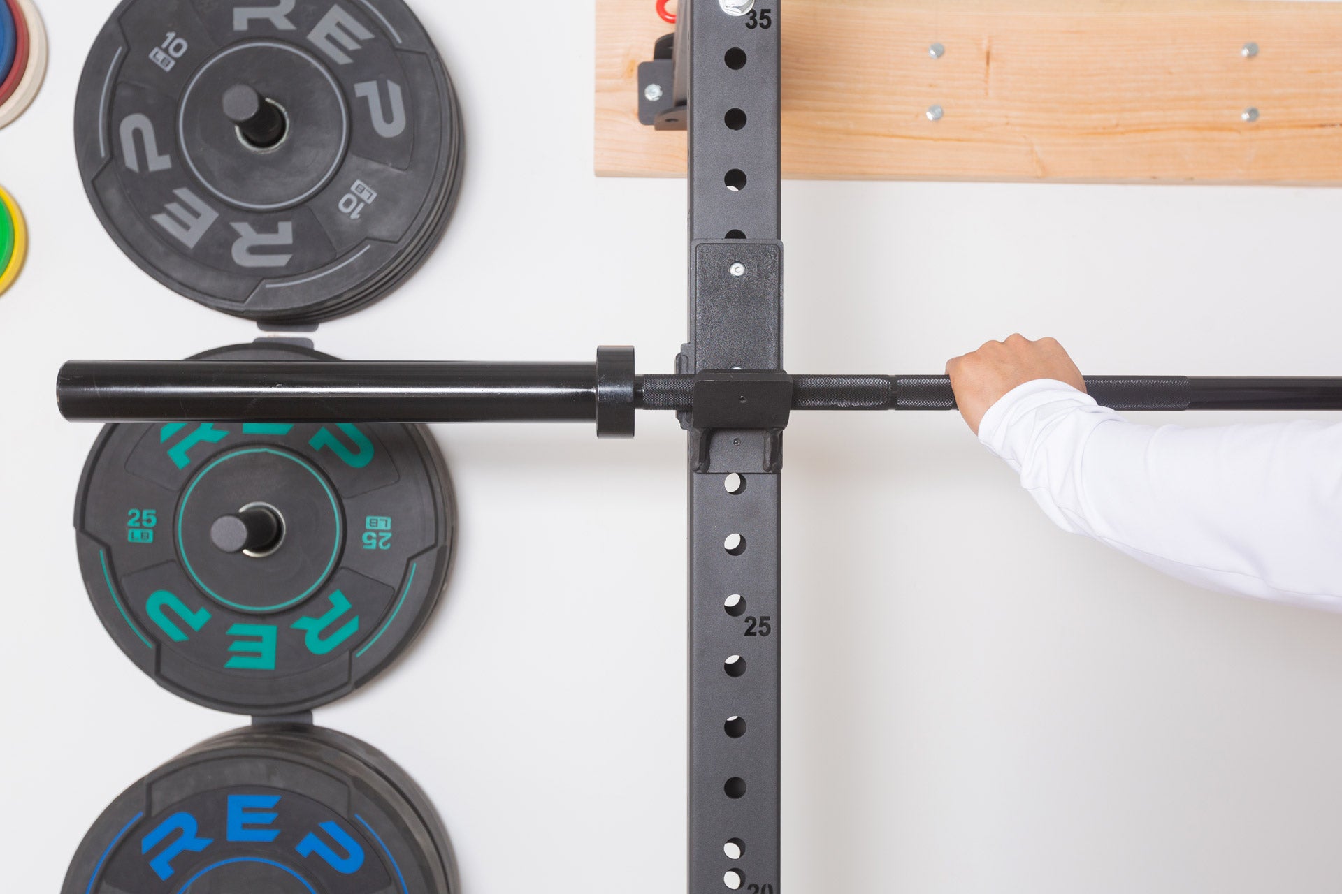 Three single Wall Mounted Plate Storage units attached to the wall and loaded with bumper plates.