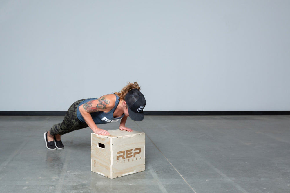 Lifter performing push-ups on a Small REP 3-in-1 Wood Plyo Box.