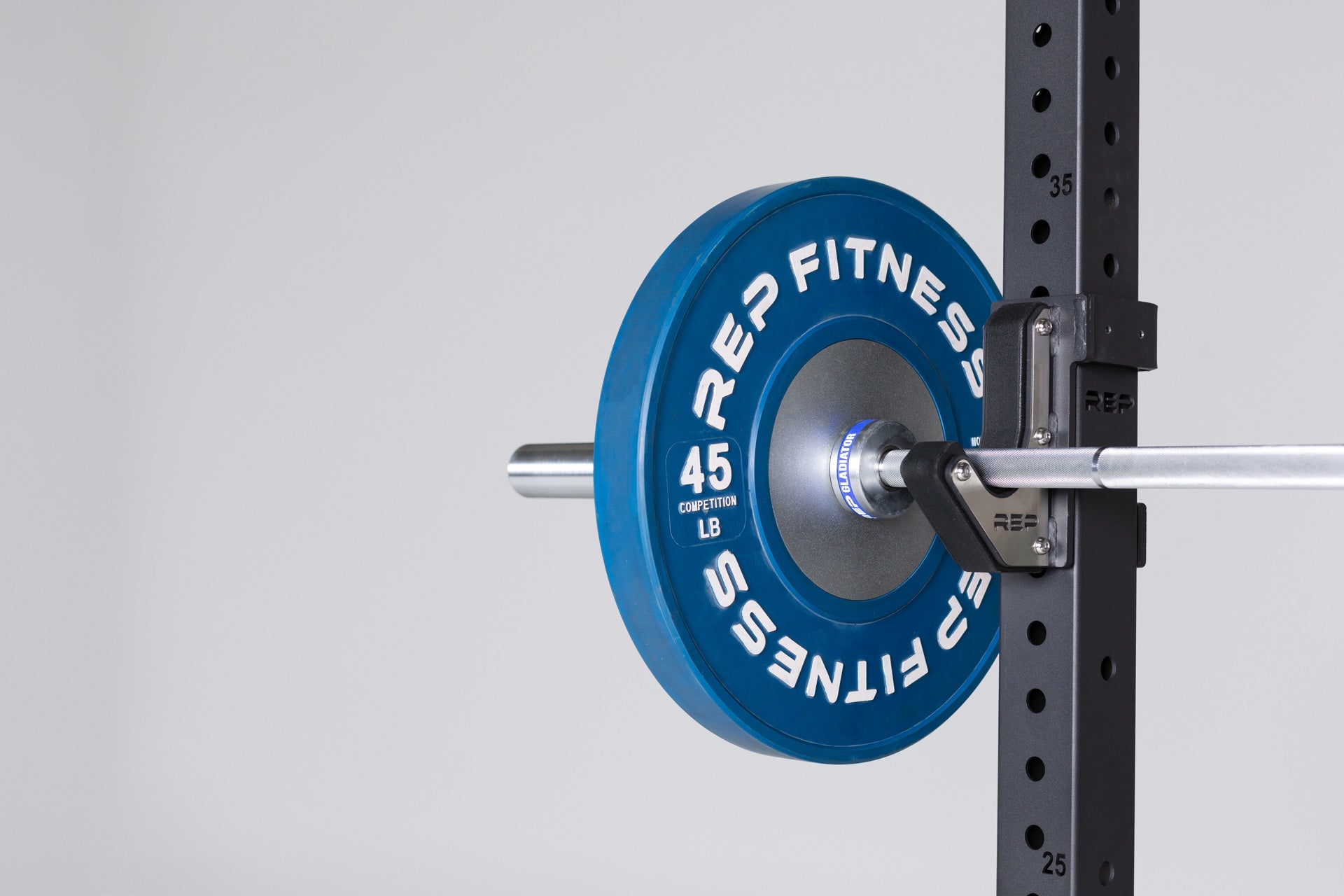Close-up view of a racked barbell loaded with a blue 45lb competition bumper plate.