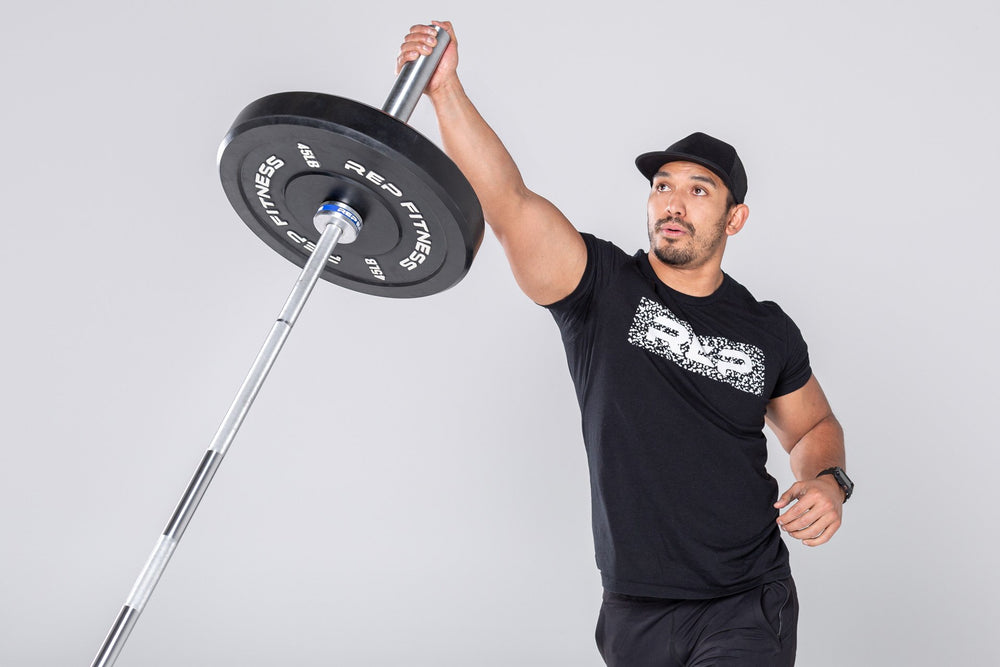 Lifter performing a single-arm overhead press with a loaded barbell in the REP Free Standing Landmine.