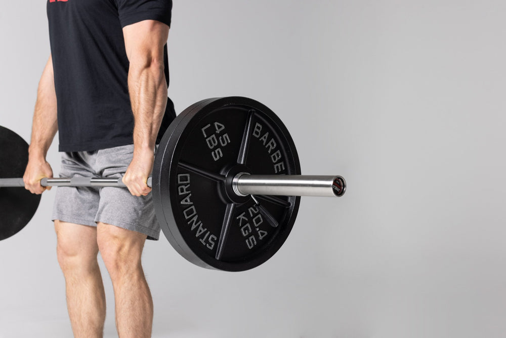 Lifter at the top position of a deadlift using a barbell loaded with two pairs of 45lb Old School Iron Plates and spring clips.