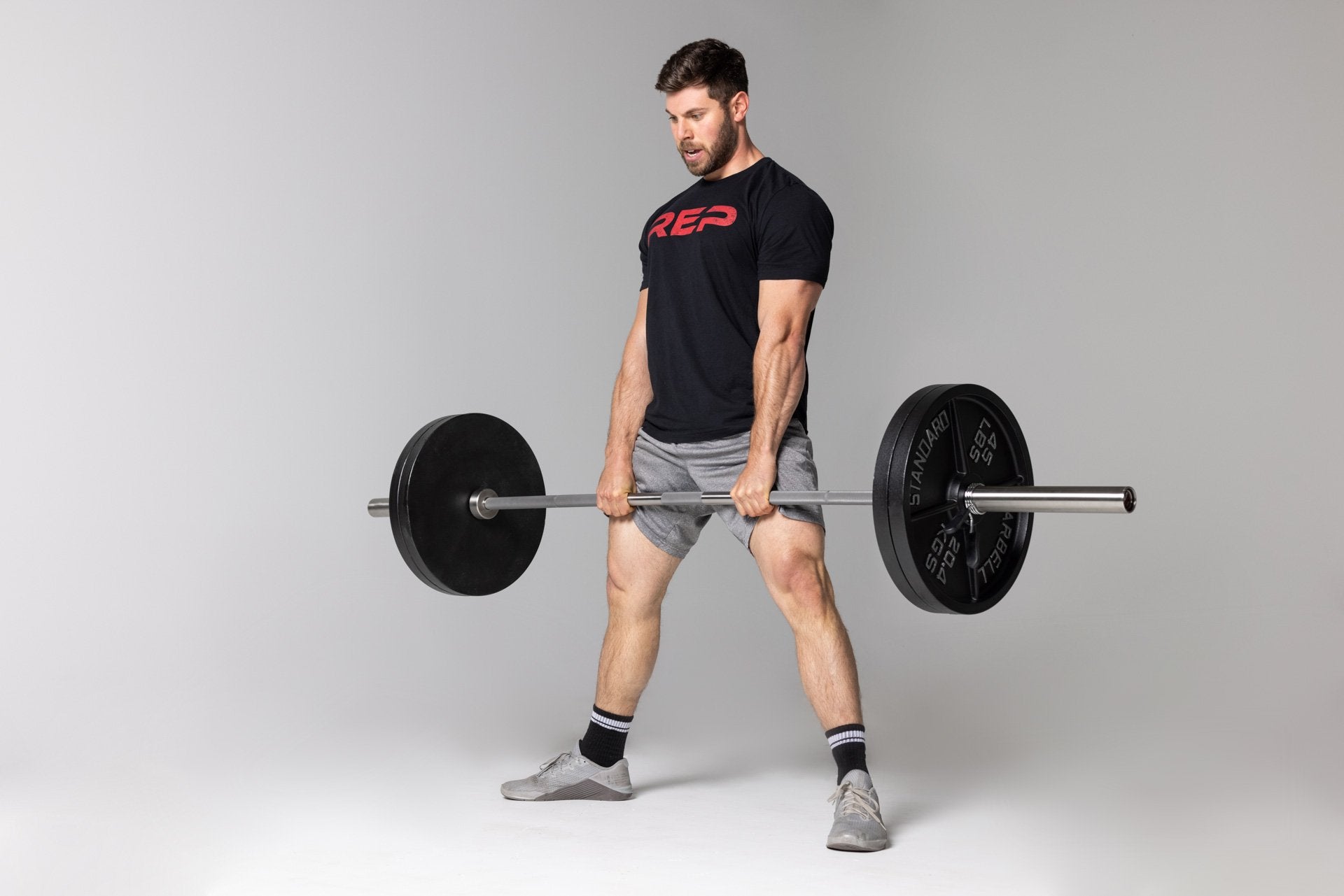 Lifter at the top position of a sumo-stance deadlift using a barbell loaded with two pairs of 45lb Old School Iron Plates and spring clips.