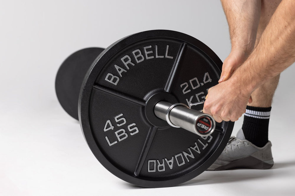 Lifter putting a spring clip onto a barbell loaded with 45lb Old School Iron Plates.